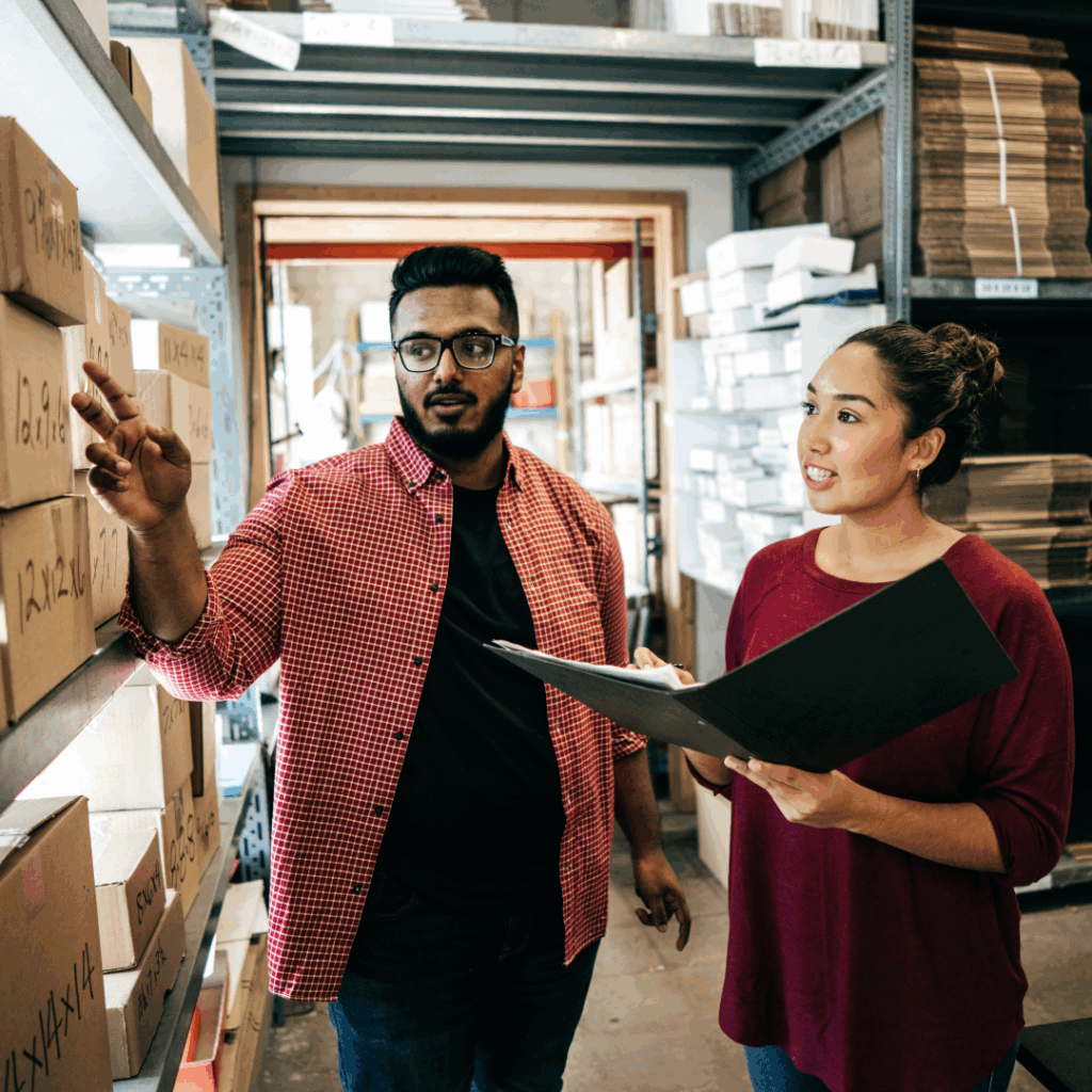two people standing next to shelves of boxes
